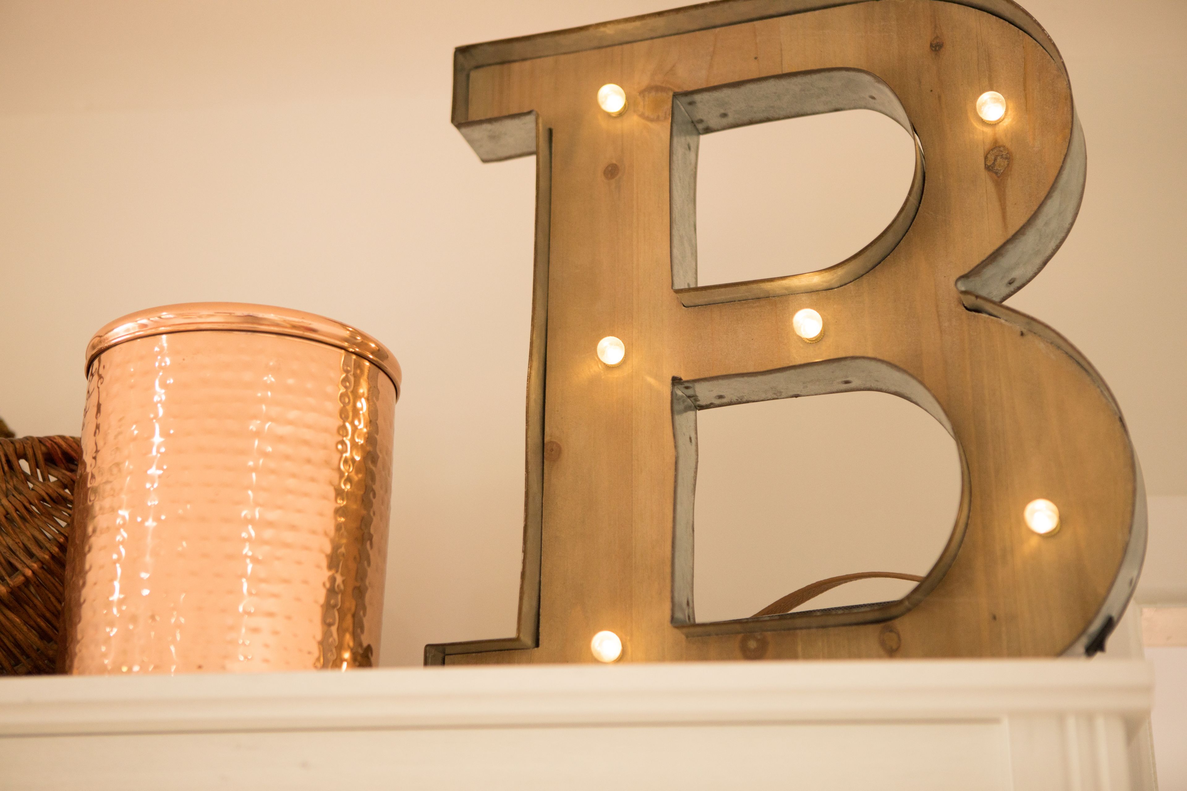 Une lettre « B » en bois illuminée, un vase texturé et un panier.