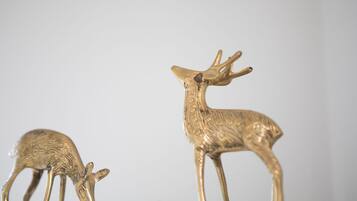 Two golden deer figurines on a white surface against a plain background.