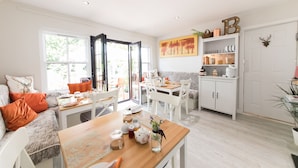 A bright, open-plan living space with a dining area, kitchen, and a large window providing natural light. - JustB (Edinburgh)