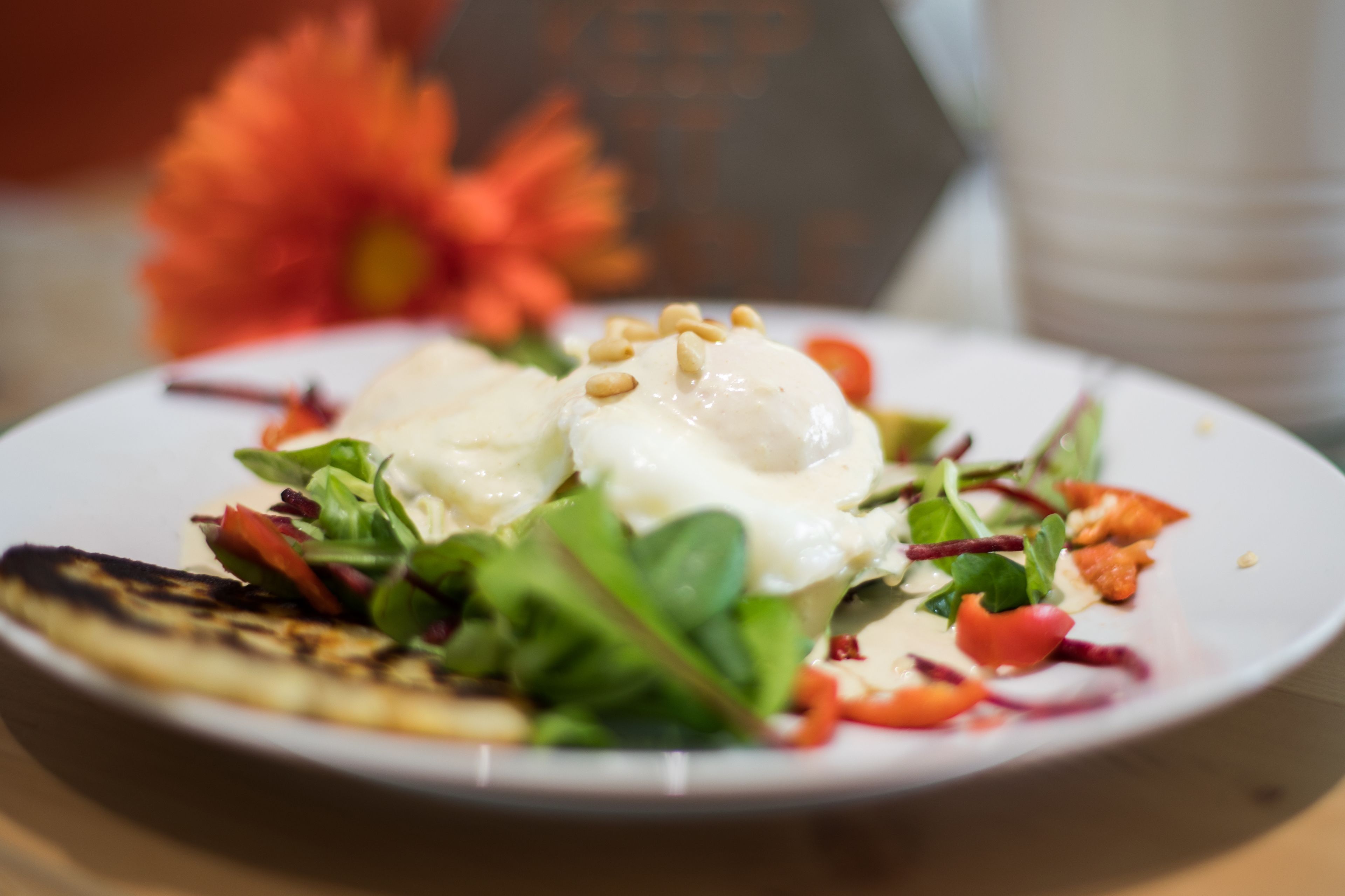 A plate of food with a poached egg, greens, and a grilled item.