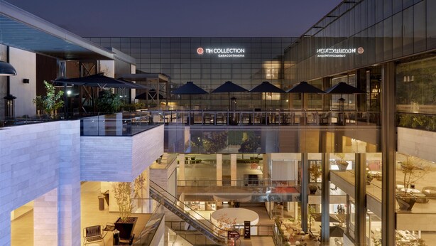 Un hôtel moderne avec un intérieur contemporain, de nombreux étages, des rampes en verre et des espaces de détente en plein air.