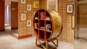 Un couloir doté d’une bibliothèque sphérique originale, de murs recouverts de panneaux en bois et d’un sol à motifs.