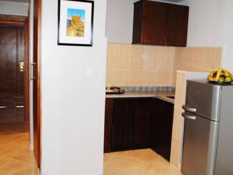 Una cucina con mobili in legno scuro, zoccolo paraschizzi in piastrelle e frigorifero in acciaio inossidabile.