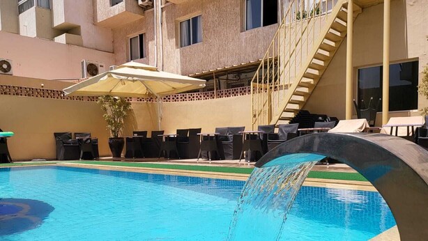 A swimming pool with a water feature, outdoor seating, and a staircase leading to an upper level.