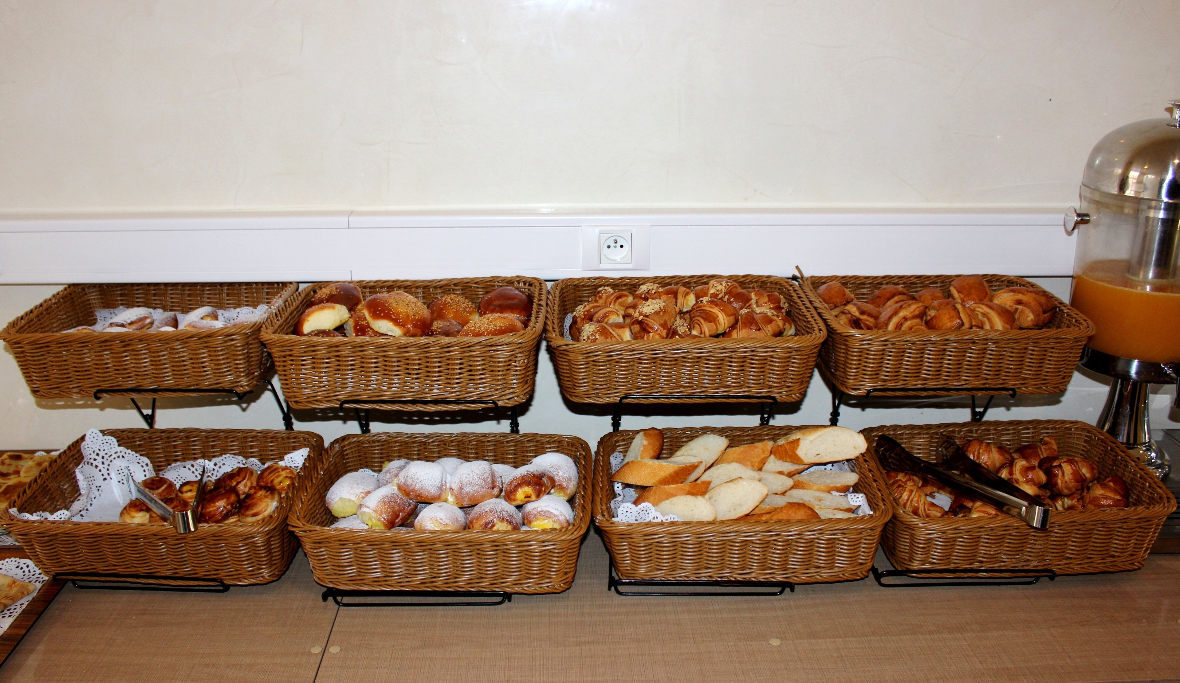 Una mesa de buffet con varias cestas de pan y pasteles.