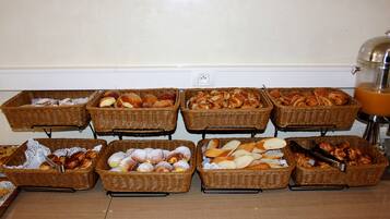 Una mesa de buffet con varias cestas de pan y pasteles.