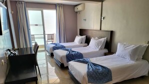 A hotel room with three beds, a desk, and a chair.