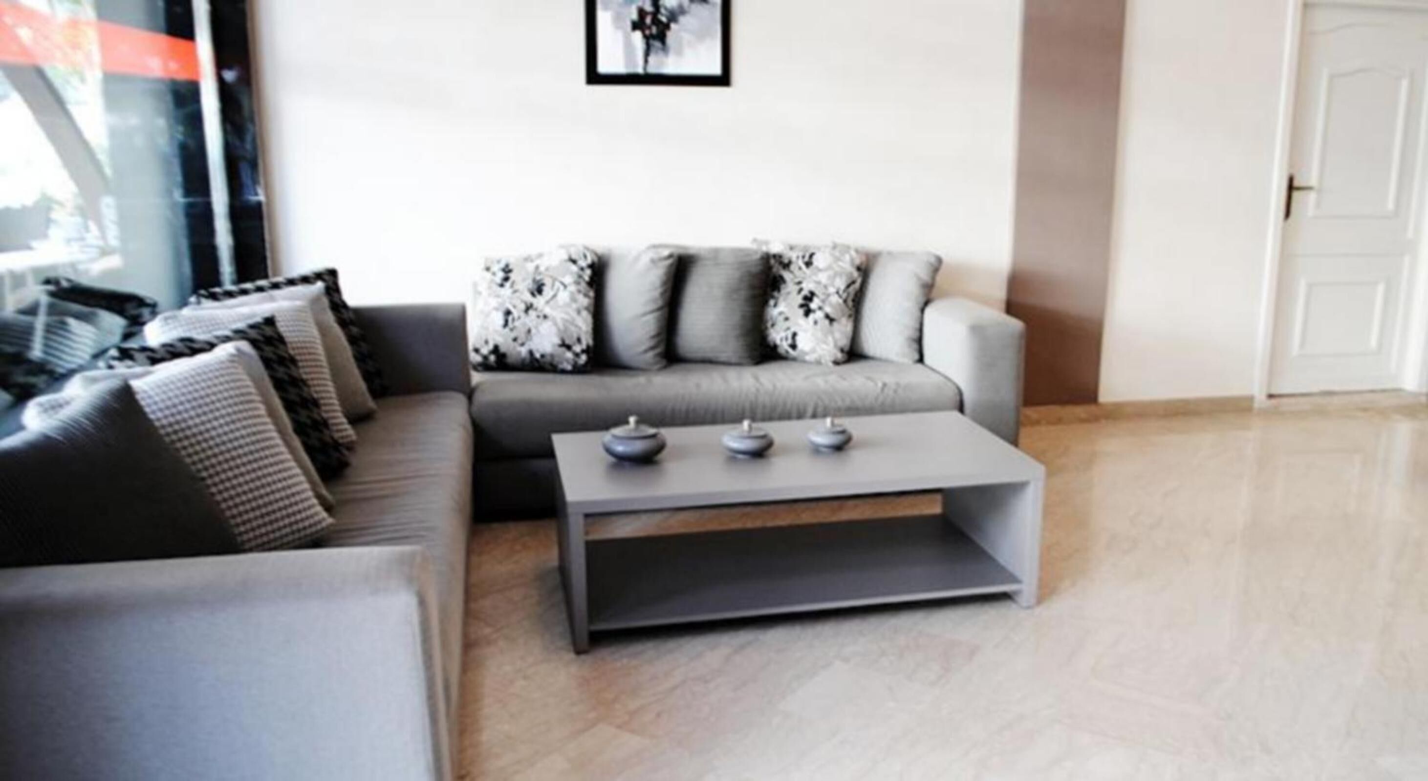 A modern living room with a grey sofa, patterned cushions, and a minimalist coffee table.
