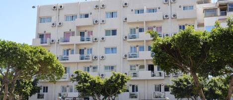 A multi-story hotel with balconies and air conditioning units.