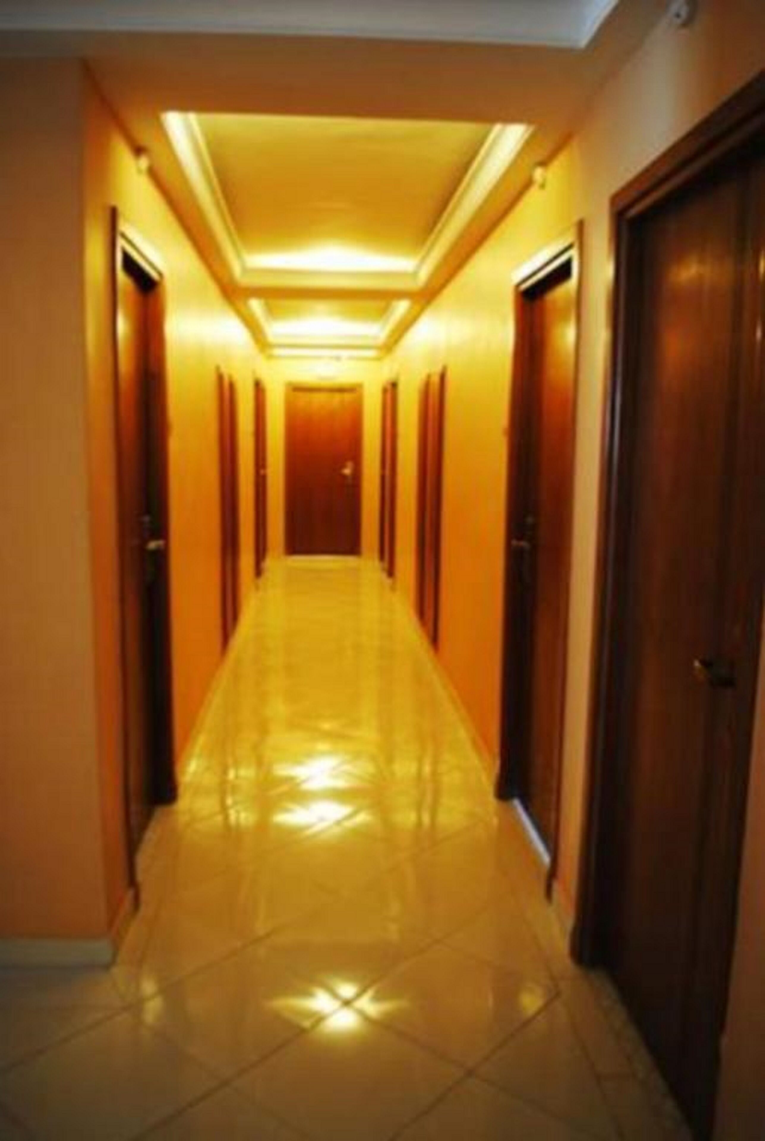 A hotel hallway with a shiny tiled floor and wooden doors.