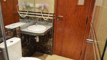 Ein kleines Badezimmer mit Toilette, zwei Waschbecken und einem Spiegel.