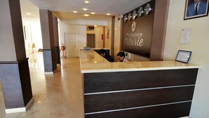 A reception desk with a dark wood finish and a sign that reads "Résidence Fleurie".
