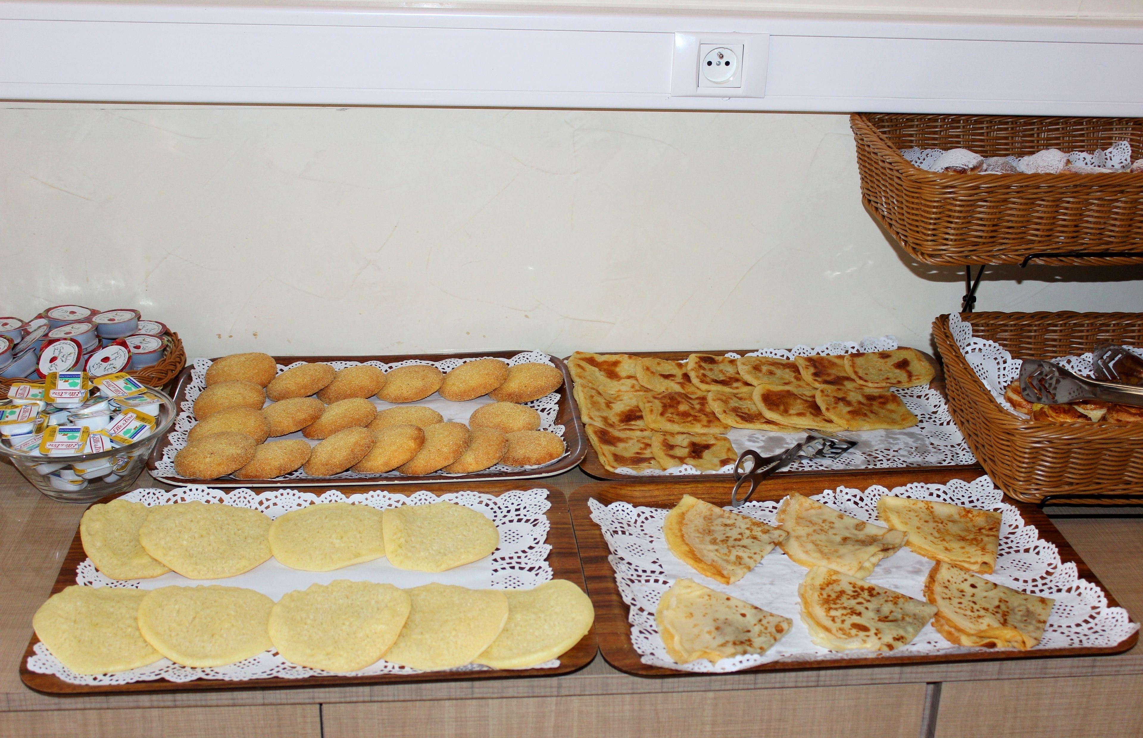 Een buffet met verschillende soorten eten, zoals koekjes, gebak en brood.