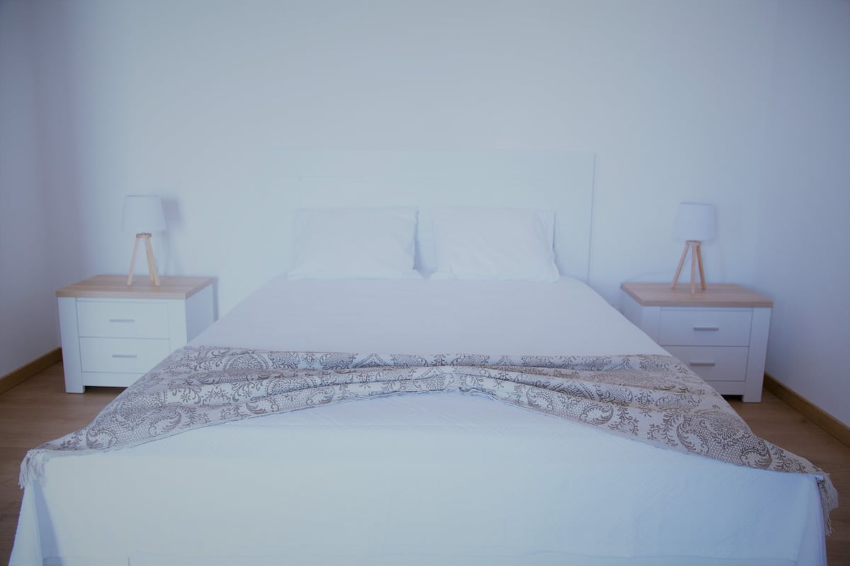 A bedroom with a bed, two bedside tables, and two lamps.