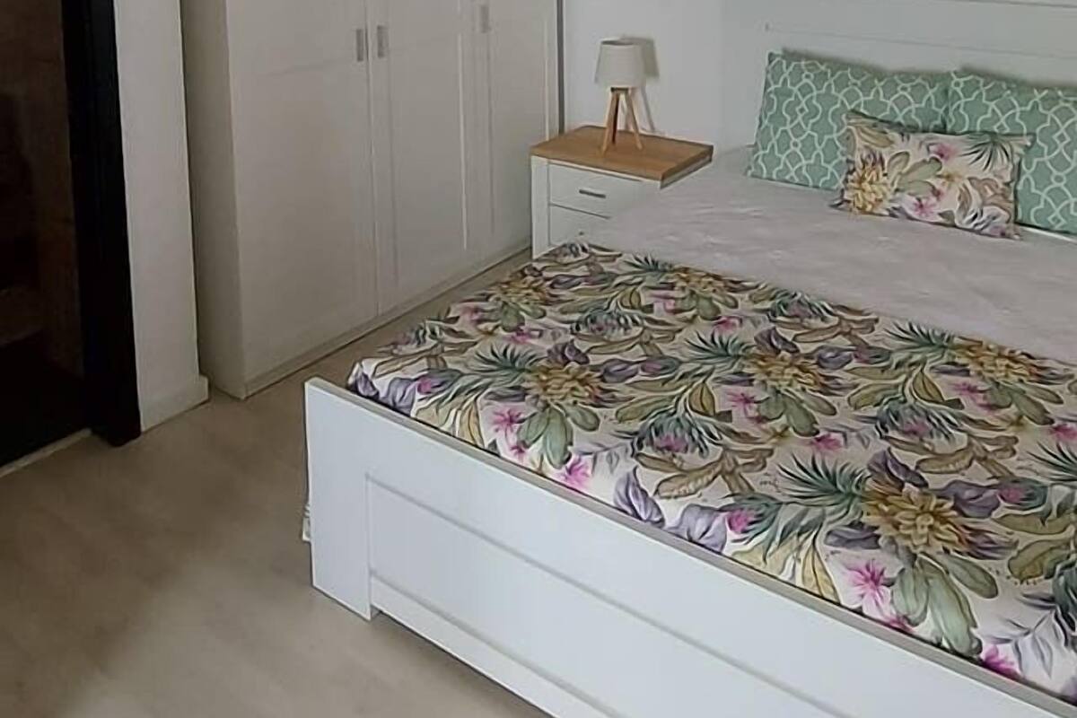 A bedroom with a bed, a wardrobe, and a nightstand.