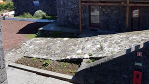 A stone building with a tiled roof, a wooden balcony, and a view of the sea. - Sara Village (Sao Roque do Pico)