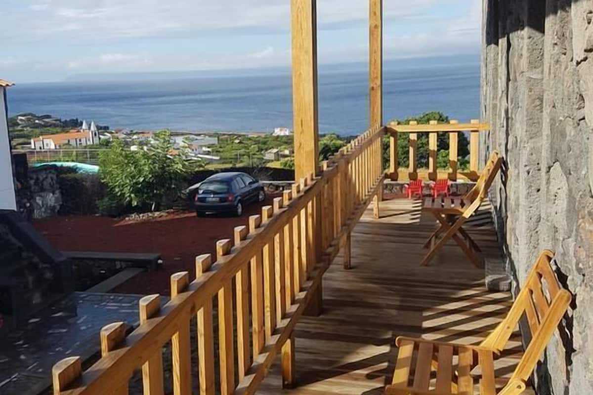 A wooden deck with a railing overlooking a scenic view of the ocean and a town.