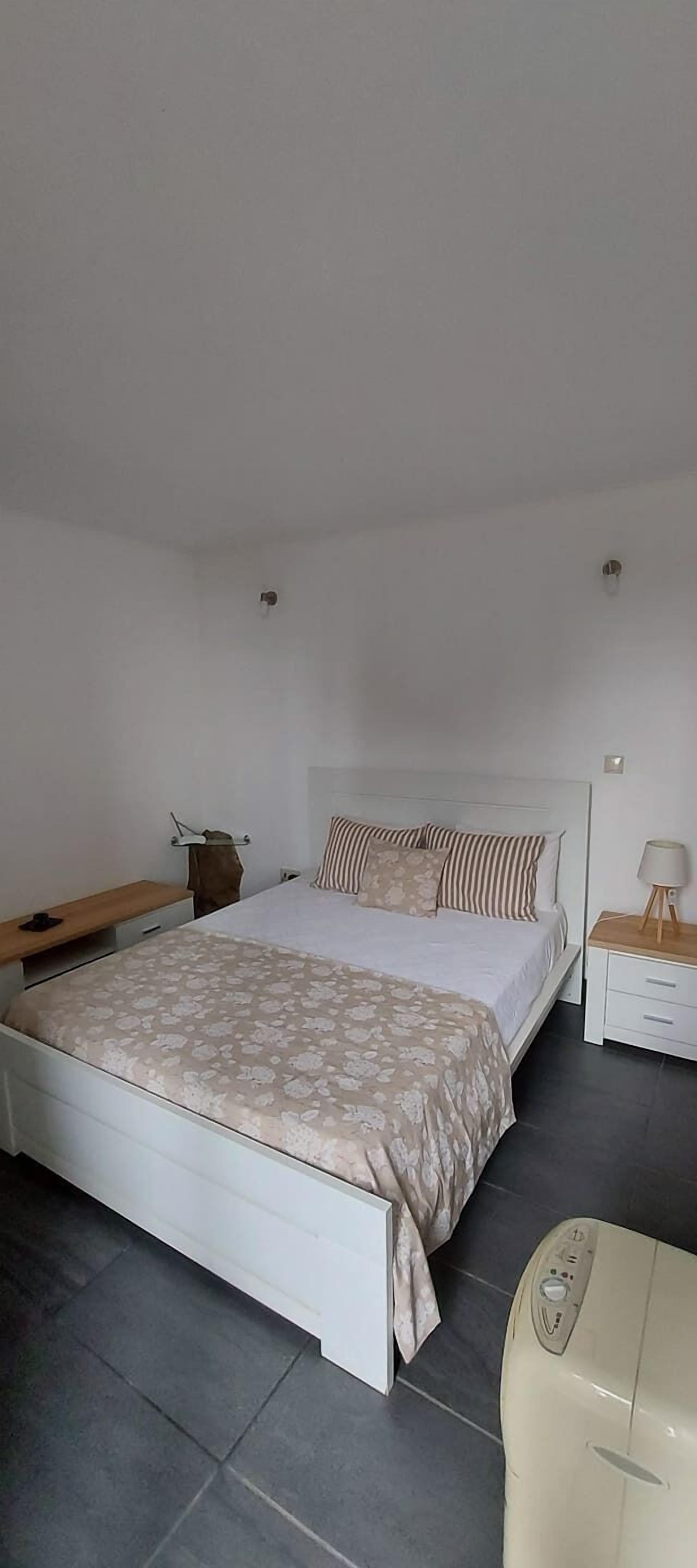 Une chambre à coucher comprenant un lit, des tables de chevet, un radiateur et une armoire.