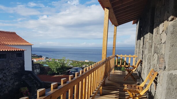 A wooden deck with a railing overlooking a coastal view. - Sara Village (Sao Roque do Pico)