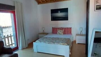 A bedroom with a wooden ceiling, a bed with a red and white pillow, a nightstand, a dresser, and a large mirror.