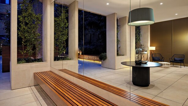 A modern interior with a wooden bench, a round table, and a hanging light fixture. - Monarch House Serviced Apartments (London)
