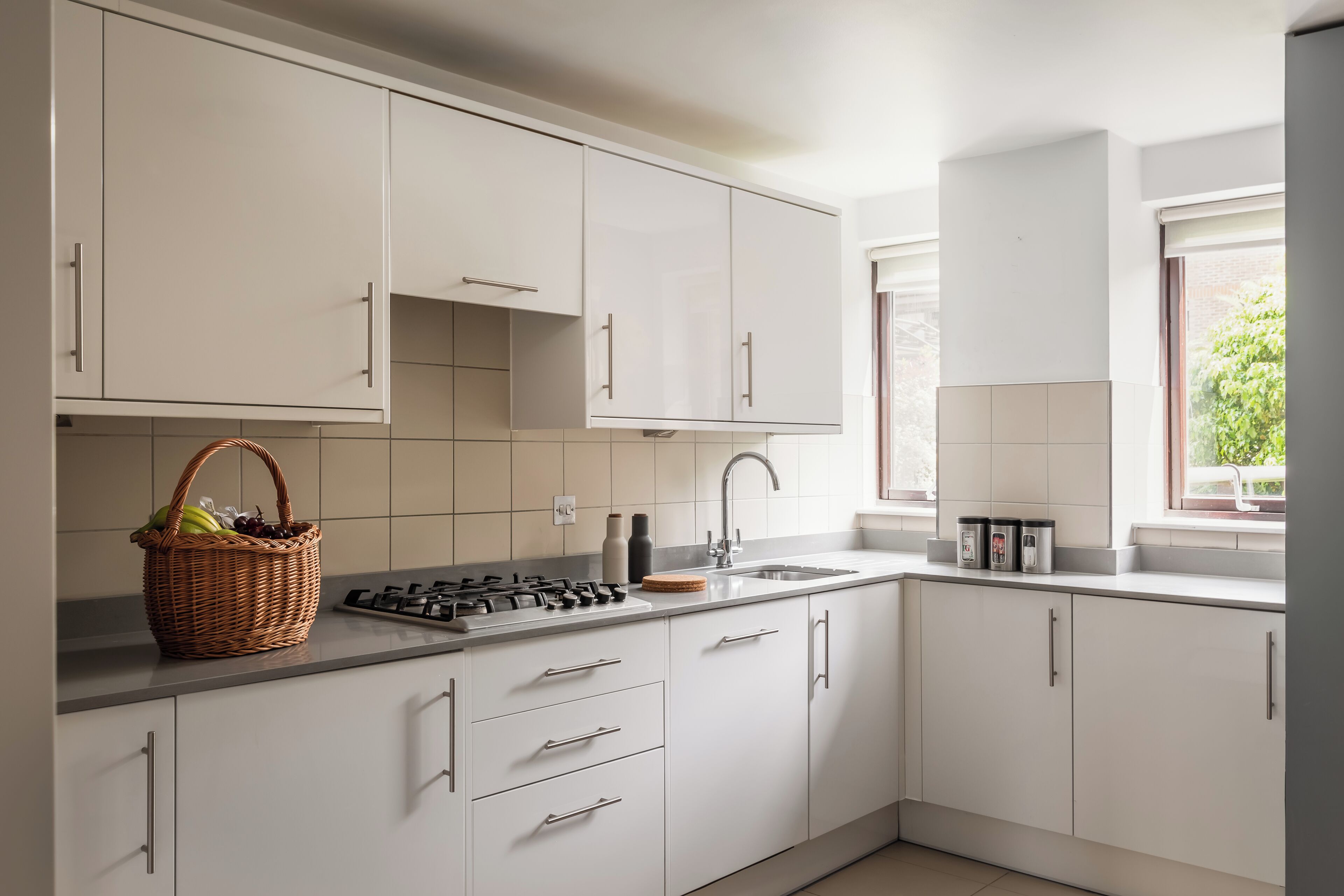 Une cuisine moderne avec des meubles blancs, une cuisinière à gaz et une fenêtre qui laisse entrer la lumière naturelle.