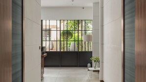 A modern hallway with a tiled floor, wooden paneling, and a large window with a view of greenery outside. - Monarch House Serviced Apartments (London)