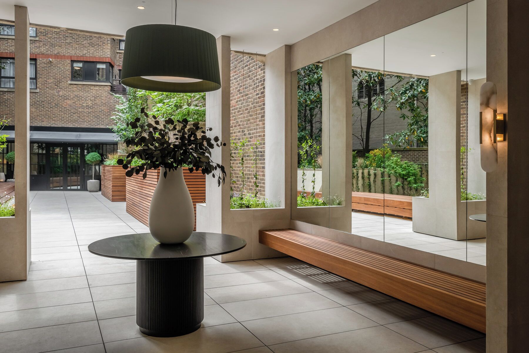 Un intérieur moderne agrémenté d’un grand vase rempli de plantes, d’une table ronde et d’un banc.