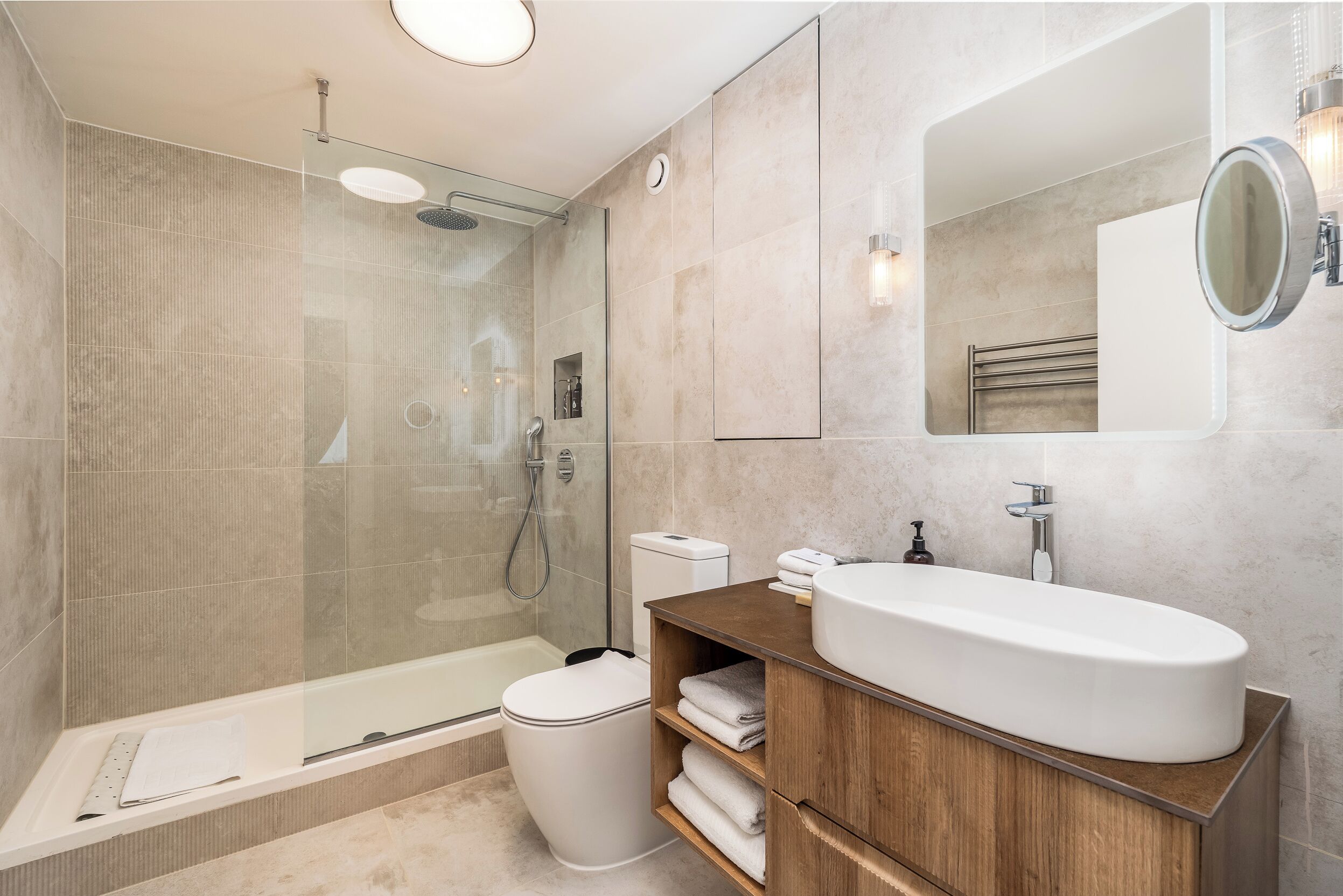 A modern bathroom with a glass-enclosed shower, a freestanding bathtub, a large sink, and a wooden vanity.