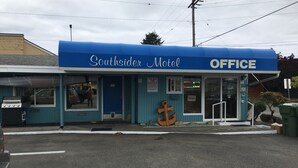 Un motel con fachada azul, una decoración con ancla y un letrero que indica la oficina.