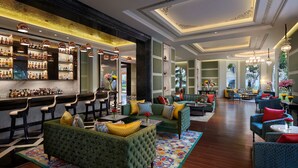 A bar area with shelves of liquor bottles, a green sofa set, and a patterned rug.