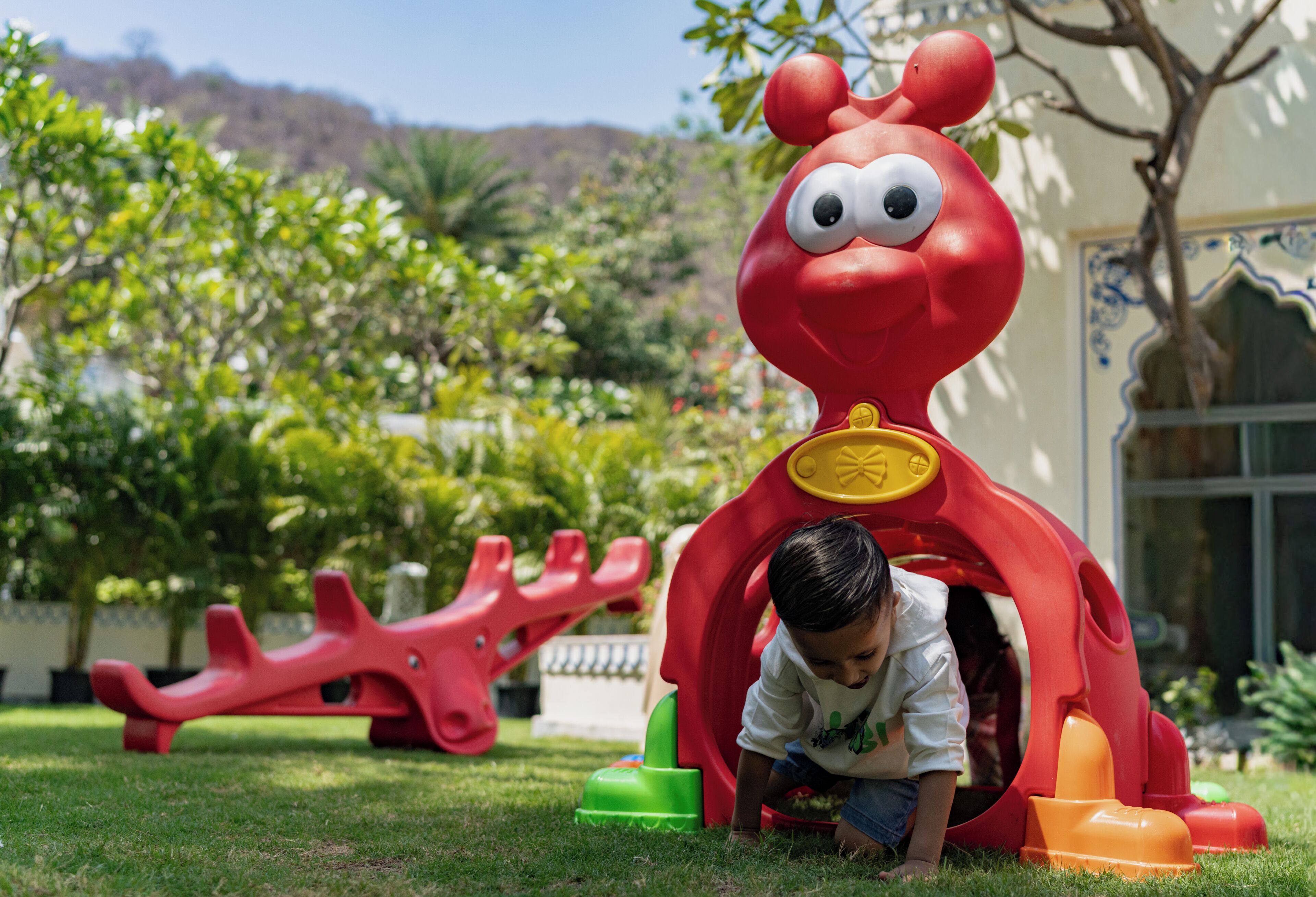 Un niño jugando en un parque infantil rojo con un tobogán y elementos para escalar.