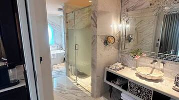 Un baño moderno con un espejo grande, suelo de mármol y cabina de ducha de vidrio.