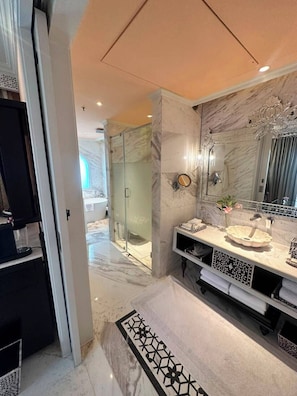Uma casa de banho moderna com um espelho grande, soalho em mármore e cabine de duche em vidro.