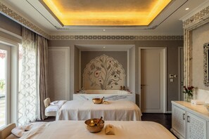 A hotel room with a large bed, a sitting area, a bathtub, and a decorative wall.