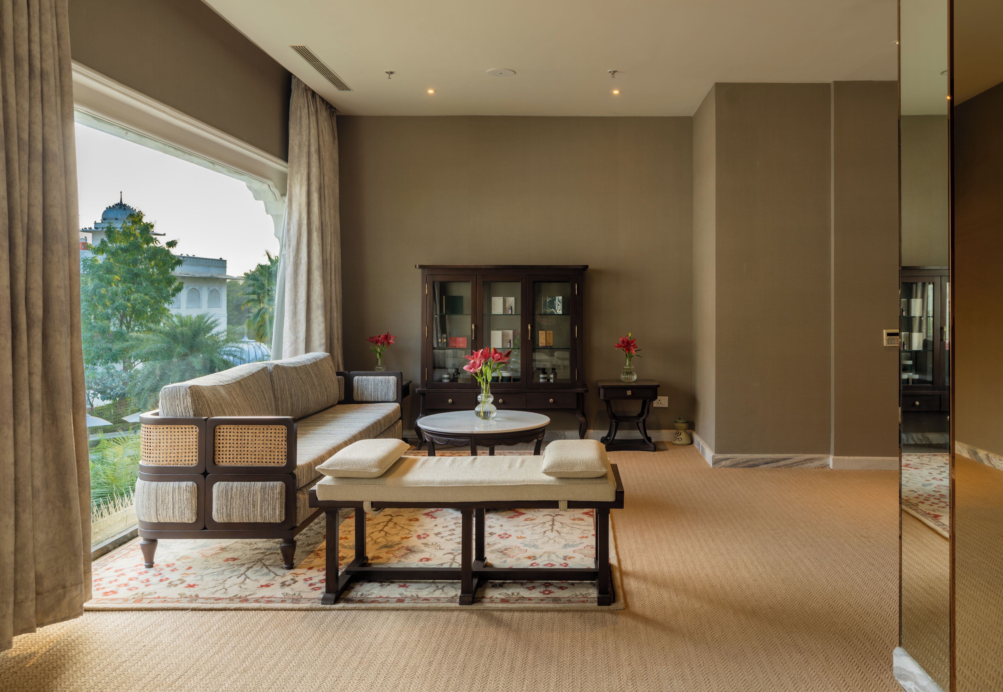 A living room with a sofa, a table, a cabinet, and a view of a building outside.