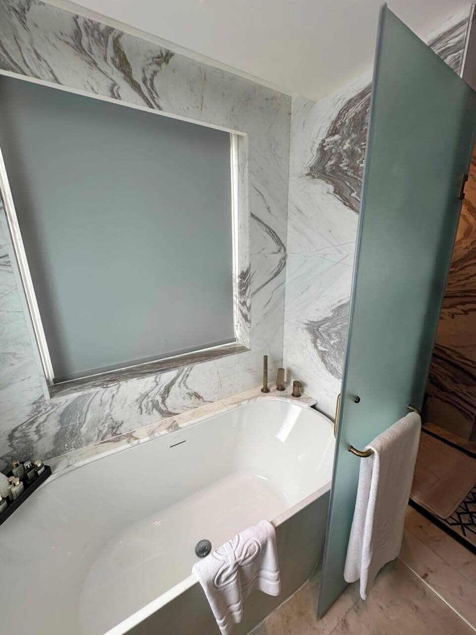 Une salle de bain avec un mur en marbre, une baignoire et un porte-serviettes.