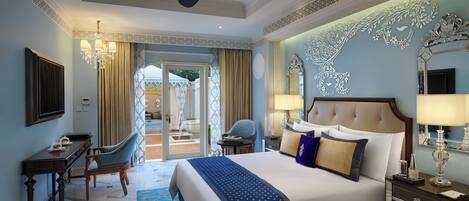 Habitación de hotel amplia con una cama grande, un escritorio y una silla. Posee un balcón con vistas al exterior.