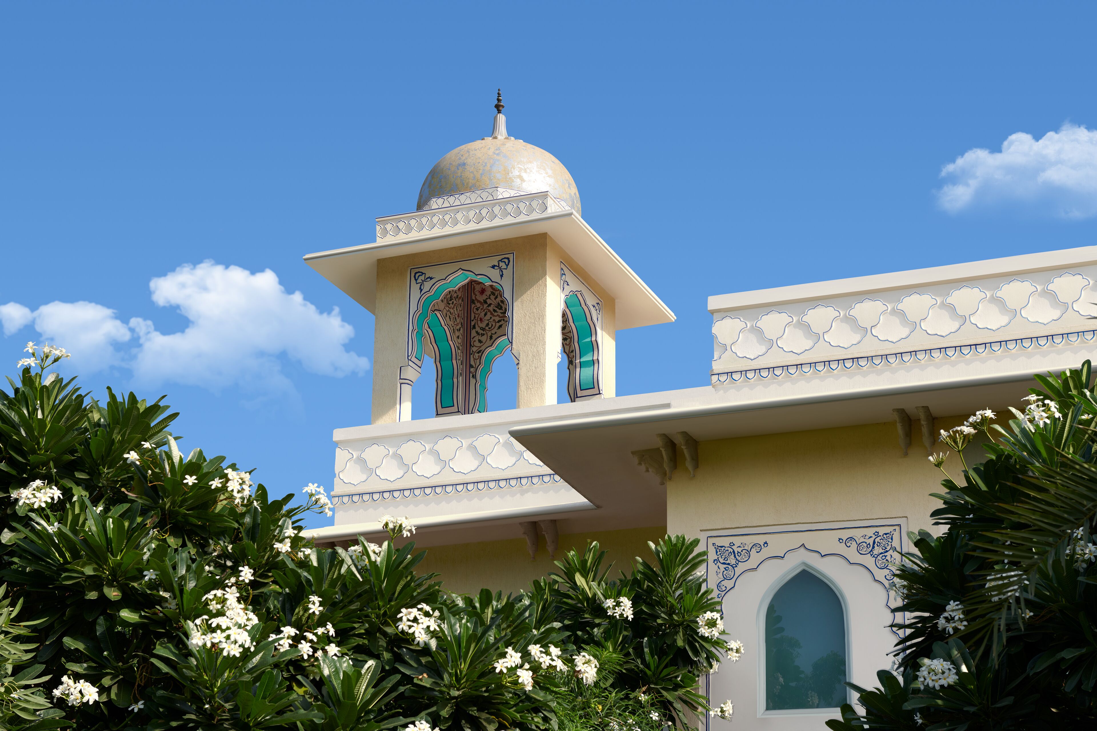 Um edifício com cúpula e janelas em arco, rodeado por vegetação exuberante.