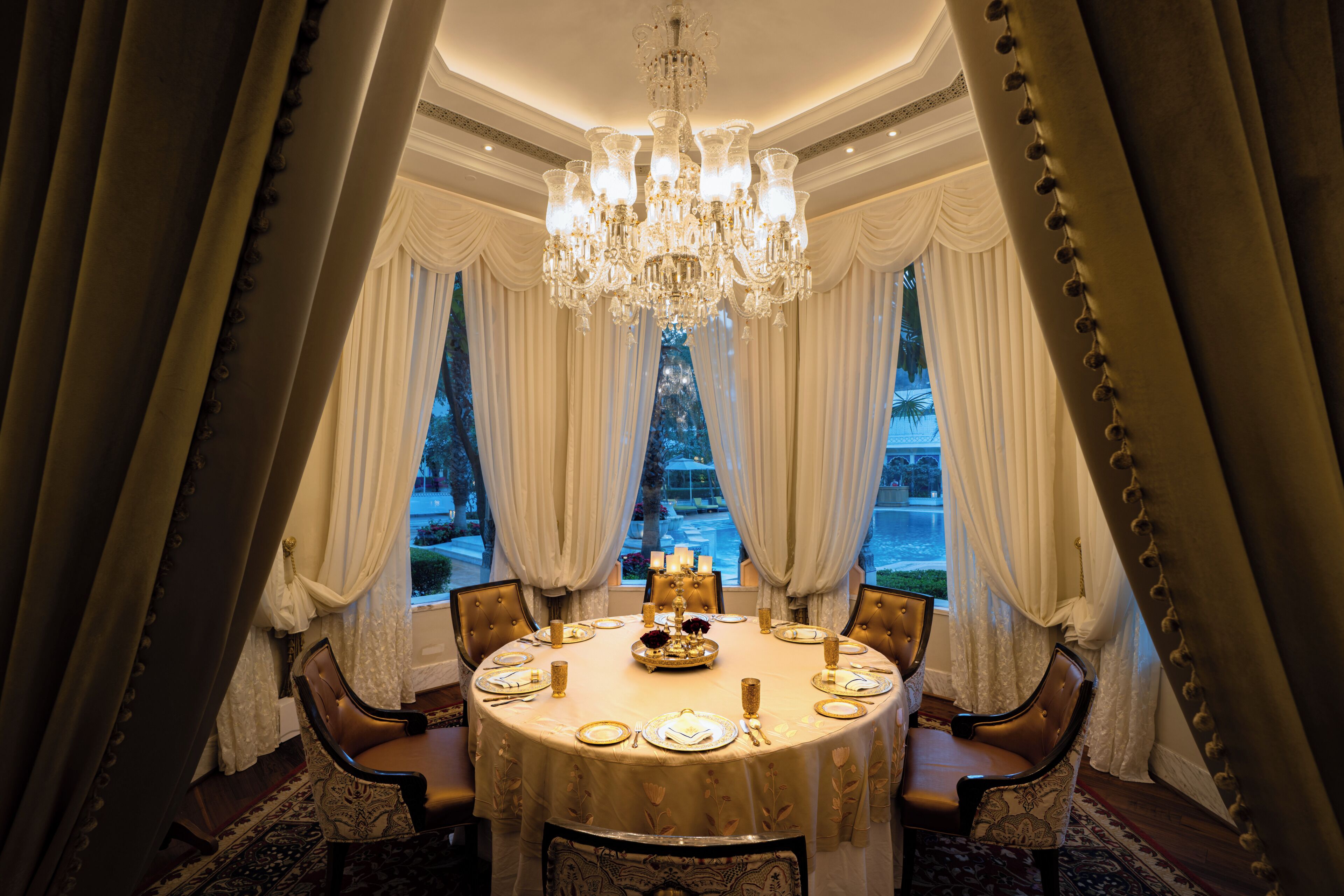 A formal dining room with a chandelier, round table, and elegant chairs.