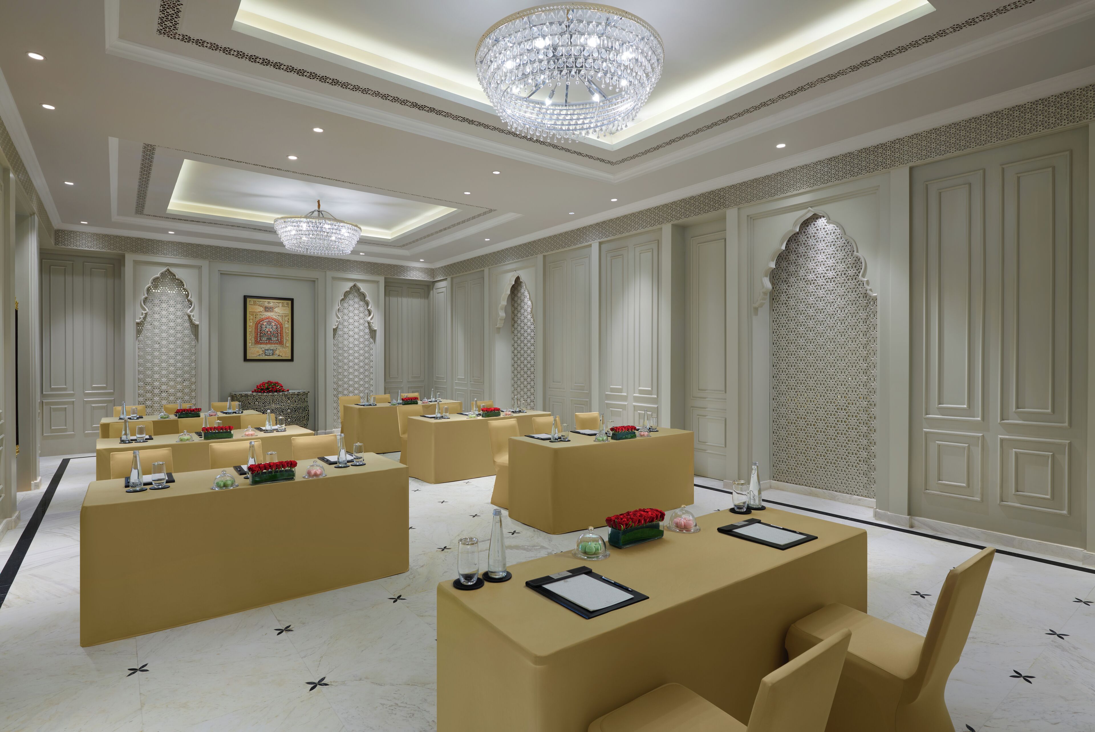 A spacious hotel lobby with multiple seating areas, a large chandelier, and decorative wall panels.