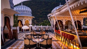 A terrace with checkered flooring, dining tables with chairs, and a bar area.