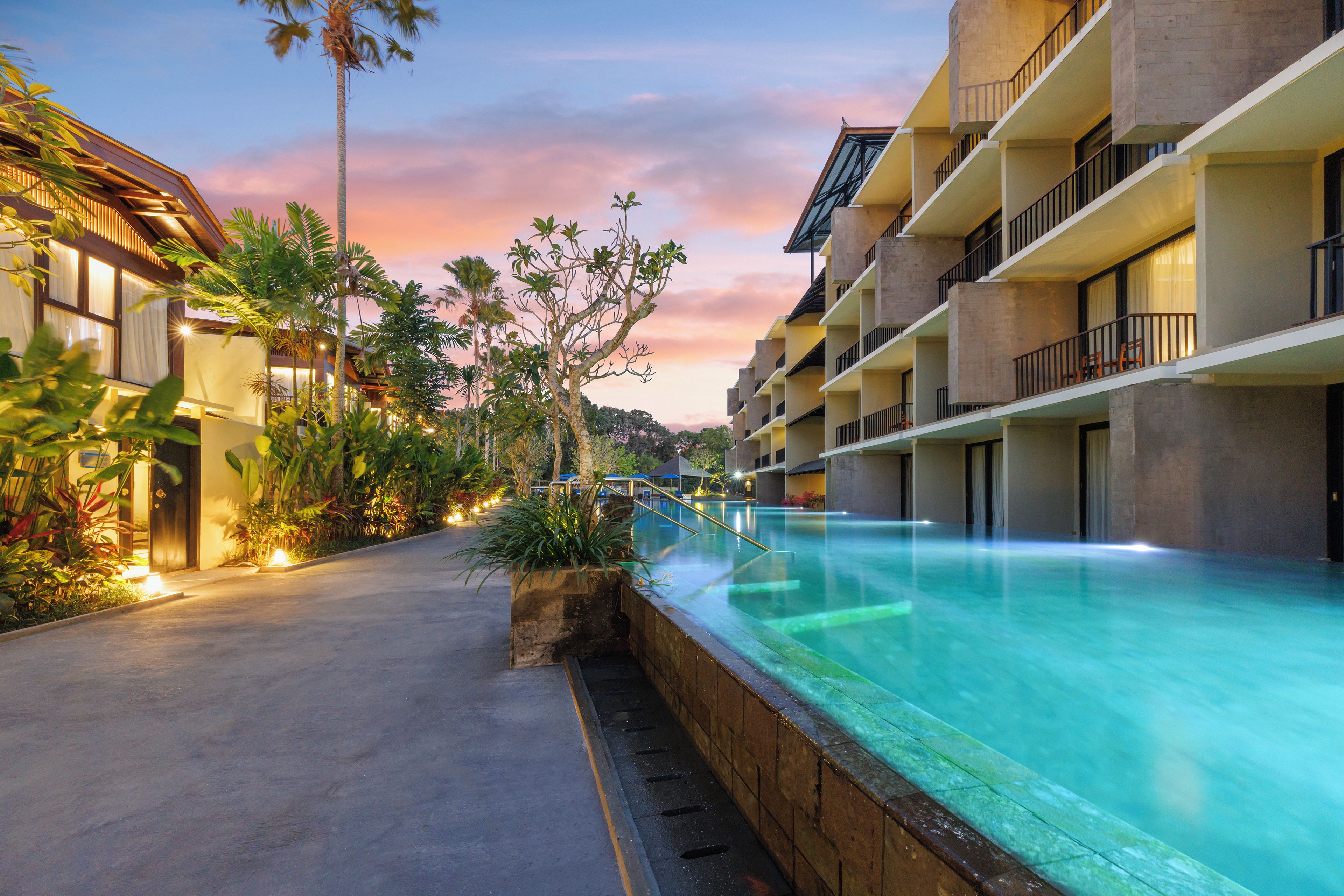 A resort with a swimming pool, multiple balconies, and lush greenery.