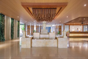 Un vestíbulo espacioso con un mostrador de recepción, un techo de madera decorativo y una fuente de piedra.