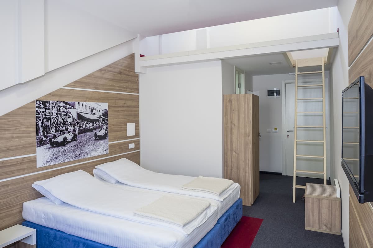 Une chambre à coucher moderne avec un lit, une tête de lit en bois, une télévision, une échelle et une affiche accrochée au mur.