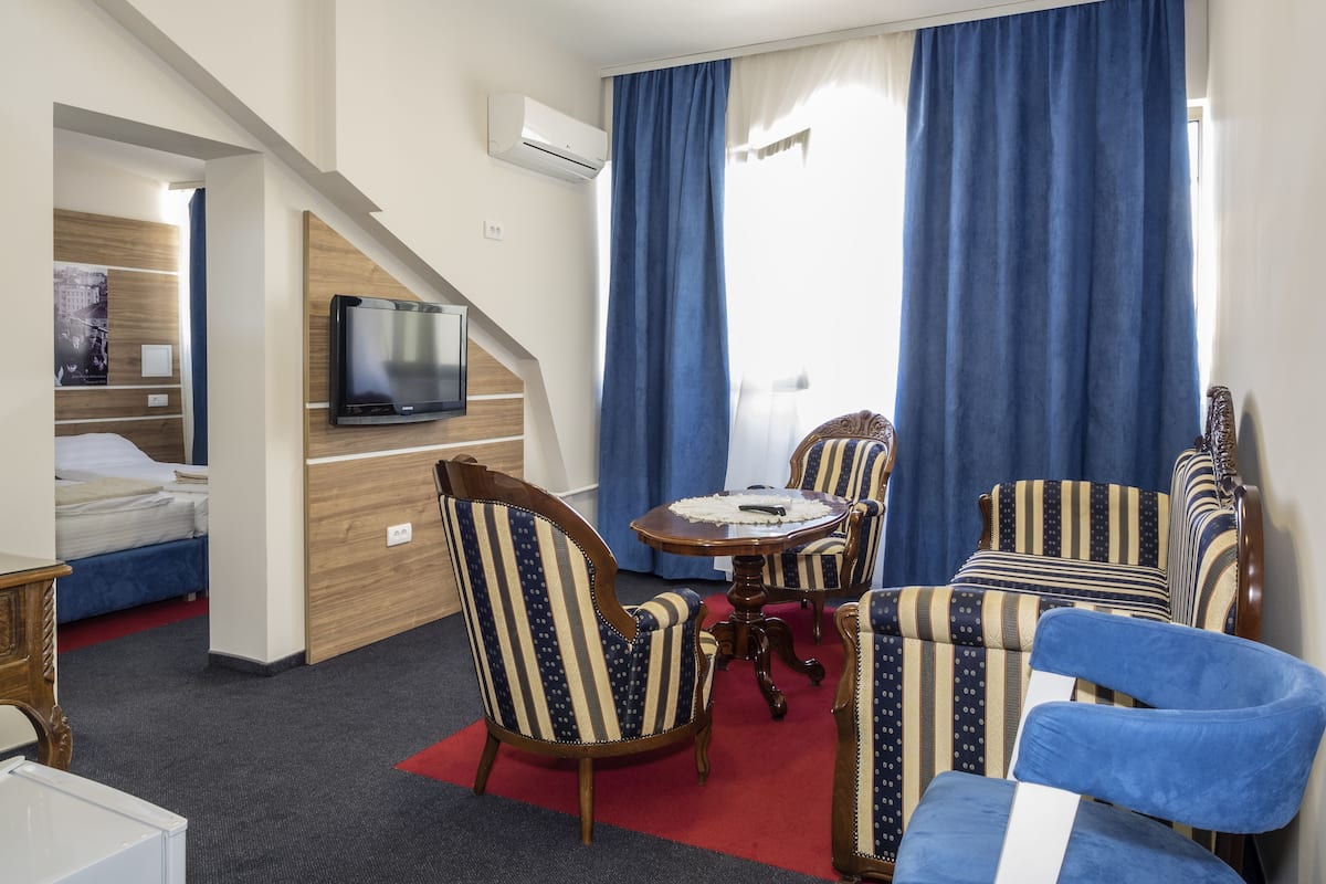 Une chambre d’hôtel comprenant un lit, une télévision, une table à manger avec des chaises et un escalier.