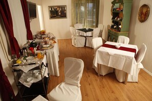 Spiseområde med hvide stole og borde, et buffetbord og et spejl på væggen.
