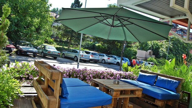 An outdoor seating area with wooden furniture and a green umbrella. - Guest House Vida (Belgrade)