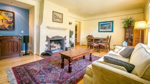 A living room with a fireplace, a sofa, a coffee table, and a dining area with chairs and a table. - 1936 Keystone Cottage - Family Friendly (Boise)
