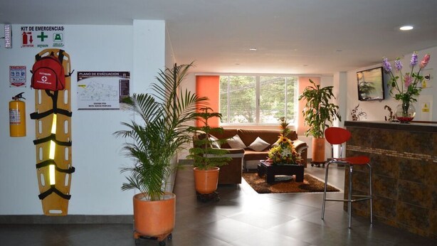 A hotel lobby with a reception desk, seating area, and emergency equipment. - Hotel Dancar (Pamplona)
